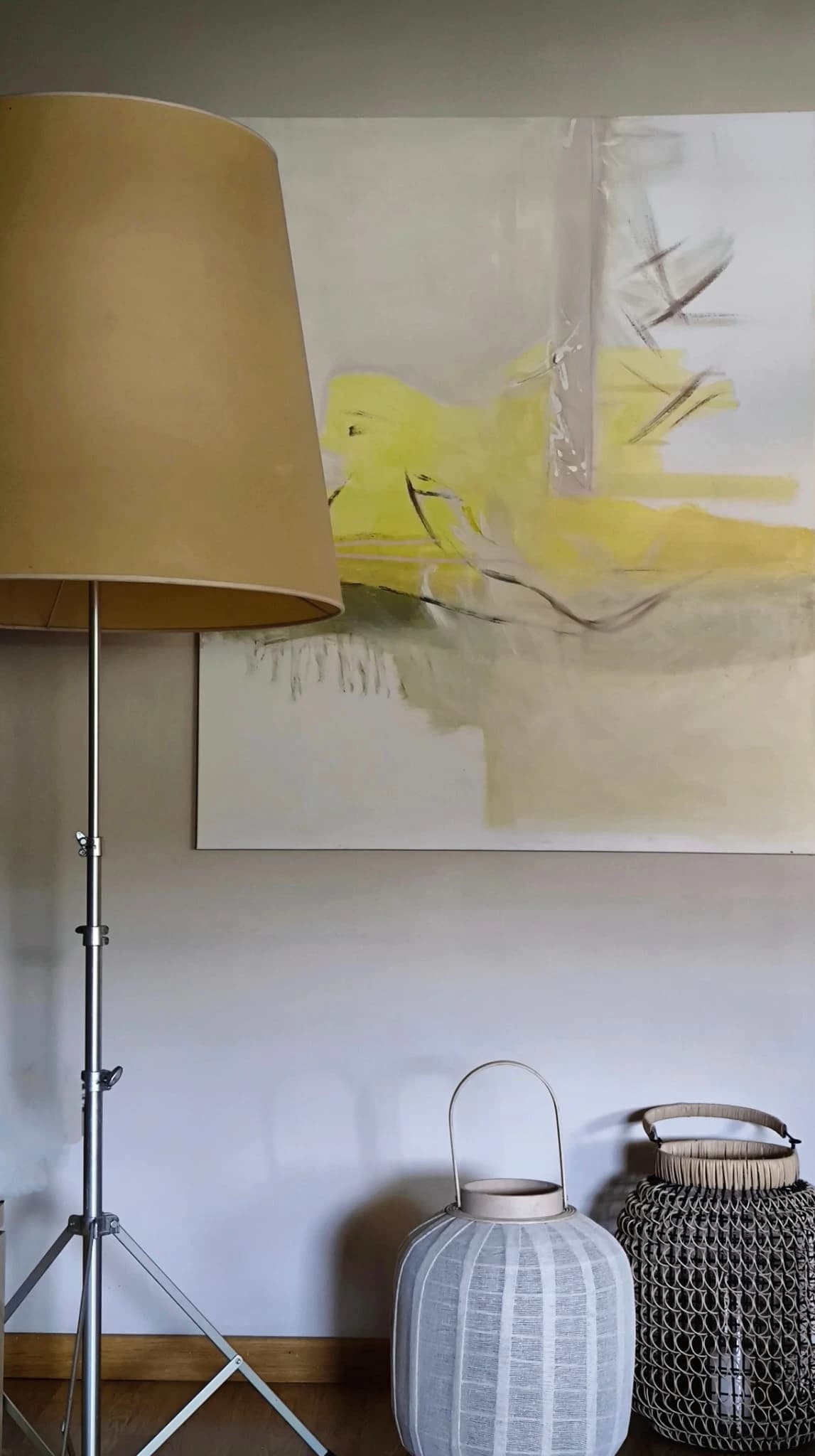 A wide yellow canvas behind a floor lamp, with woven lanterns on the floor
